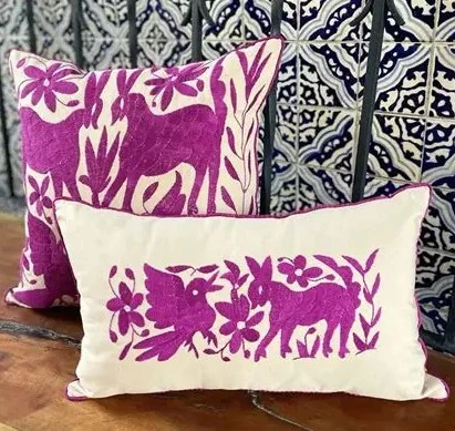 Hand-embroidered Tenango style pillow with colorful birds and floral patterns on white fabric